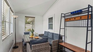 Una habitación acogedora con sofá, una mesa de comedor con una piña y una litera con estante de madera.