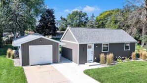 A two-story house with a garage, a front porch, and a small attached shed.