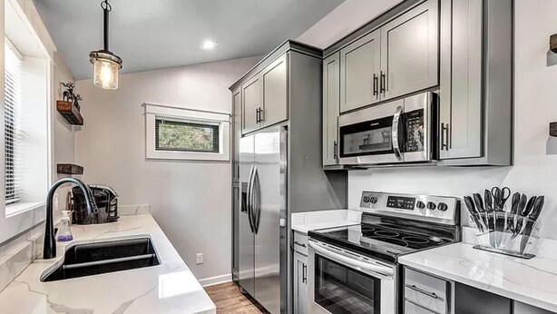 A modern kitchen with stainless steel appliances, white cabinetry, and a large island with a sink.