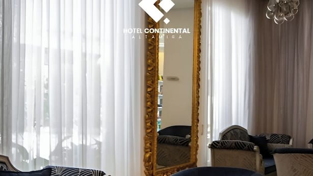 Un salon moderne doté d’un grand miroir, de sièges confortables et d’une table basse en verre.