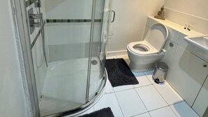 Un baño con ducha de vidrio, inodoro y lavamanos.