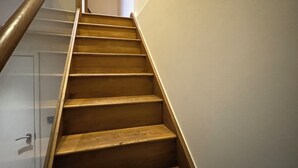 Una escalera de madera con barandilla de metal que lleva a un cuarto con una puerta blanca.