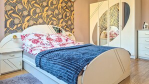 A bedroom with a bed, nightstands, a dresser, a mirror, and a patterned wallpaper. - 2 bedroom cozy home in Szczecin (Szczecin)