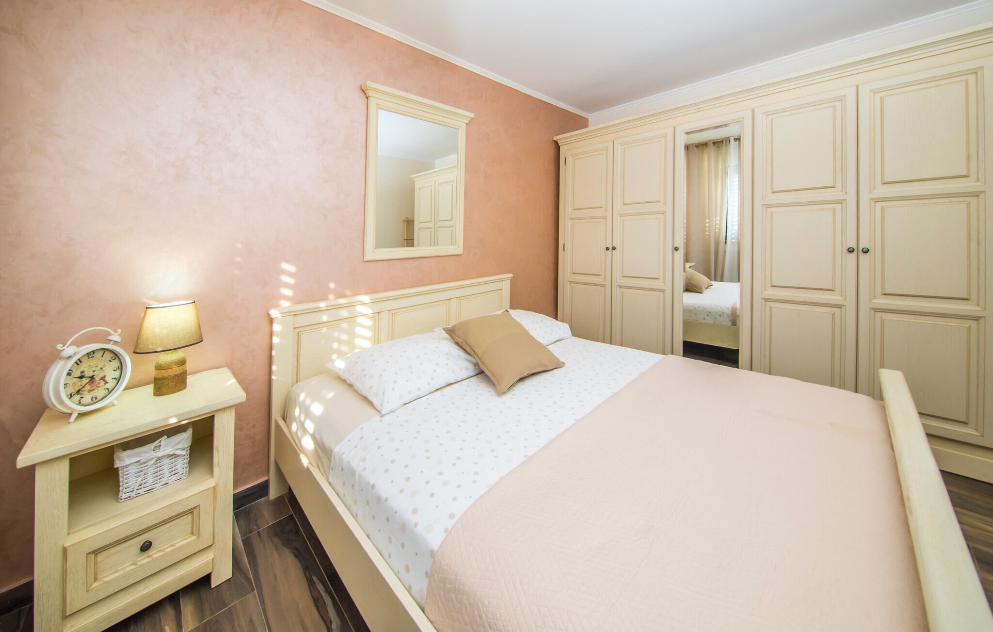 A bedroom with a bed, a nightstand with a lamp, a dresser, and a wardrobe.