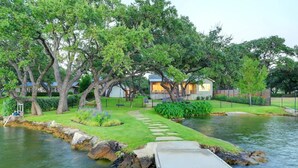 A lakeside property with a dock, stone pathway, and a house with a porch. - Packsaddle Point Luxury Lakefront w/Pool+Guest House (Kingsland)