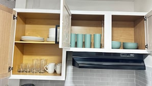 A kitchen with open cabinets displaying dishes and glassware.