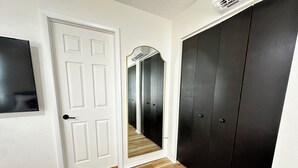 A hallway with a white door, a black wardrobe, and a mirror.