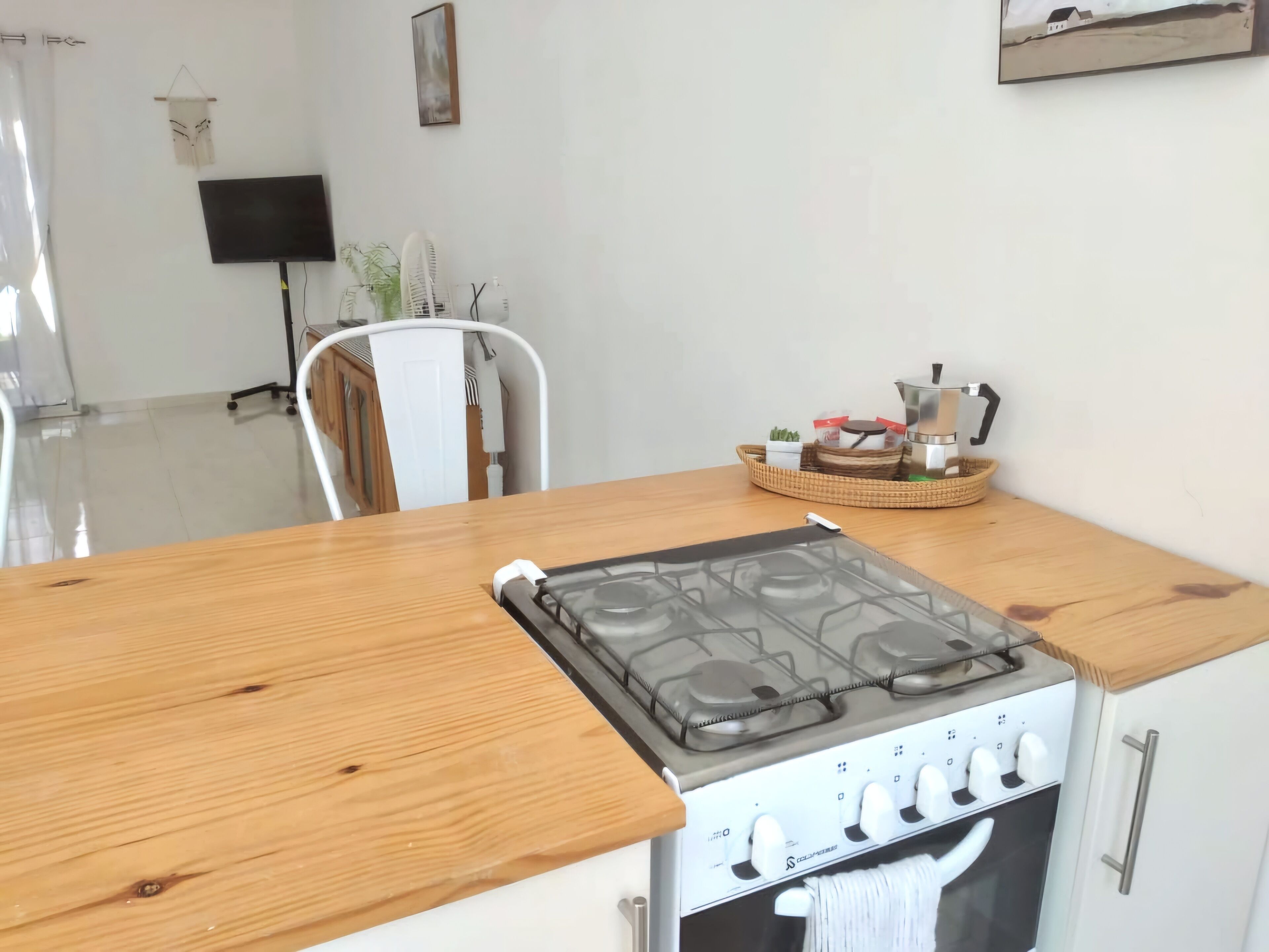Una cocina con estufa a gas, armarios blancos y encimera de madera.