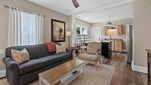Een woonkamer met een grijze bank, een houten salontafel en een plafondventilator.