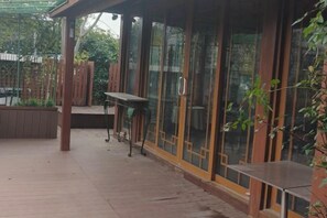 A covered outdoor area with a wooden deck, a table, and a bench. - Hangzhou West Lake Enjoyor Hotel (Hangzhou)