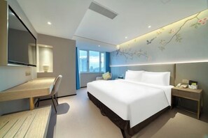 Habitació d'hotel amb llit, escriptori, cadira, tauleta de nit i una finestra gran.