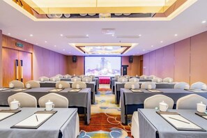 A conference room with multiple tables, chairs, and a large screen at the front. - Hangzhou West Lake Enjoyor Hotel (Hangzhou)