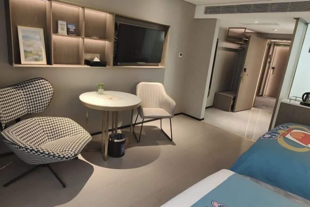 Une chambre d’hôtel comprenant un lit, une table ronde, deux chaises, un téléviseur et un mini-bar.