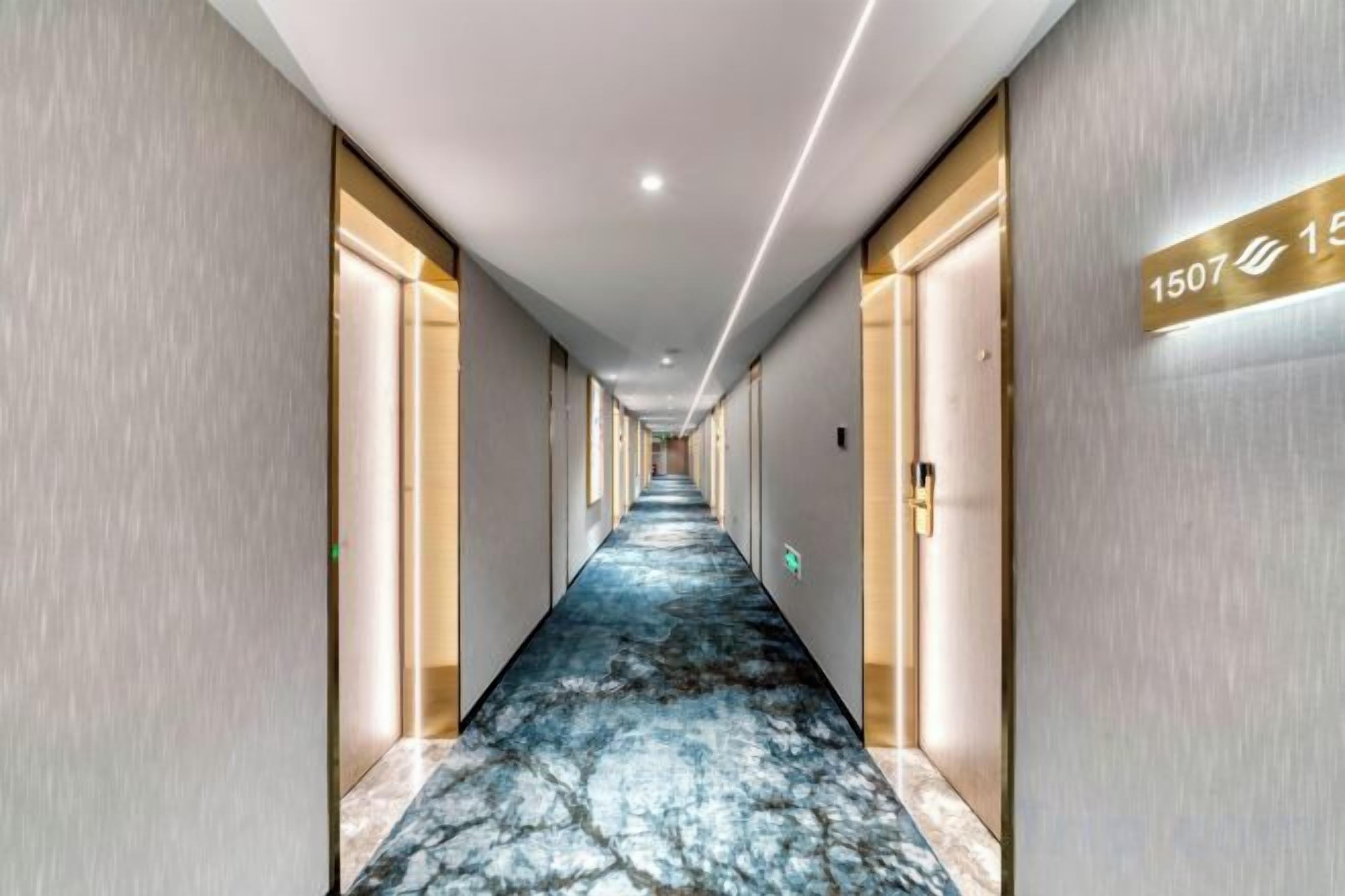 Un couloir d’hôtel avec un sol en marbre, des portes de chaque côté et un panneau indiquant le numéro de la chambre : 1507.