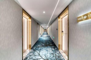 Un pasillo de hotel con piso de mármol, puertas a ambos lados y un cartel que indica la habitación 1507.