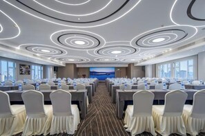 A conference room with round tables, chairs, and a large screen at the front. - Hangzhou West Lake Enjoyor Hotel (Hangzhou)