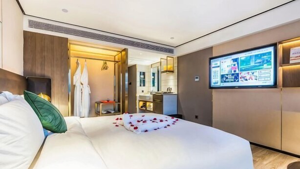 Une chambre d’hôtel équipée d’un lit, d’un téléviseur, d’un miroir et d’une kitchenette.