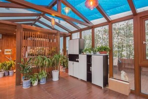 Una habitación amplia con techo de madera, cocina integrada y ventanas grandes.