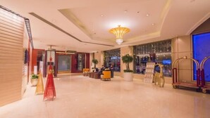 Un hall d’entrée spacieux agrémenté d’un lustre, d’un espace salon et d’un comptoir d’accueil.