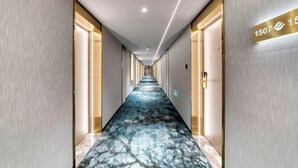 Un couloir d’hôtel avec un sol en marbre, des portes de part et d’autre, et une pancarte indiquant le numéro de chambre : 1507.