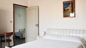 A bedroom with a bed, a chair, a nightstand, a wall-mounted lamp, and a door leading to another room. - RM03 - Senigallia, three-room apartment facing the sea (Senigallia)