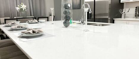 Una cocina moderna con una isla grande, electrodomésticos de acero inoxidable y un diseño minimalista.