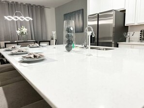 Una cocina moderna con una isla grande, electrodomésticos de acero inoxidable y un diseño minimalista.