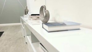 Ein modernes, minimalistisches Zimmer mit einem weißen Schreibtisch, einem Buch, einem Telefon und einer dekorativen Metallskulptur.