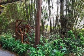 A rustic water wheel surrounded by lush greenery and bamboo. - Gujia Inn (Zhaoping)