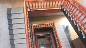 Una escalera de varios niveles con barandillas de madera y peldaños negros.