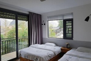 Een slaapkamer met balkon, een bed, nachtkastje en raam met zonwering.