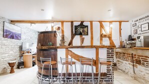 Un coin bar rustique avec des poutres en bois, un grand tonneau et des tabourets de bar.