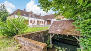 Une maison traditionnelle avec une façade en briques, un toit en pente et un petit jardin.