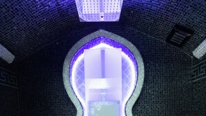 A spa room with a modern design, featuring a central illuminated panel, a patterned wall, and a tiled floor. - guest house eros suite (Rome)