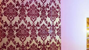 A bathroom with a patterned wallpaper, a tiled floor, and a white bathtub.