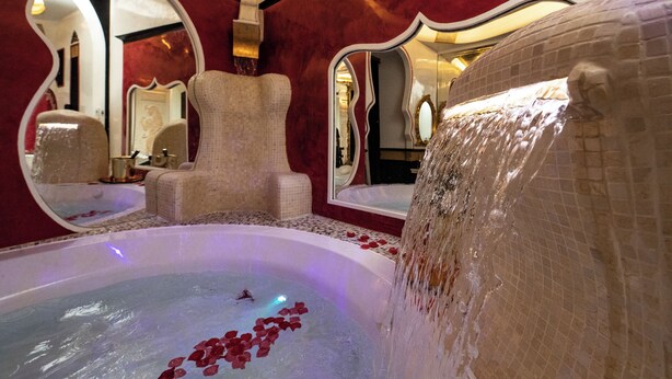 A luxurious bathroom with a large bathtub, multiple mirrors, and a waterfall feature. - guest house eros suite (Rome)