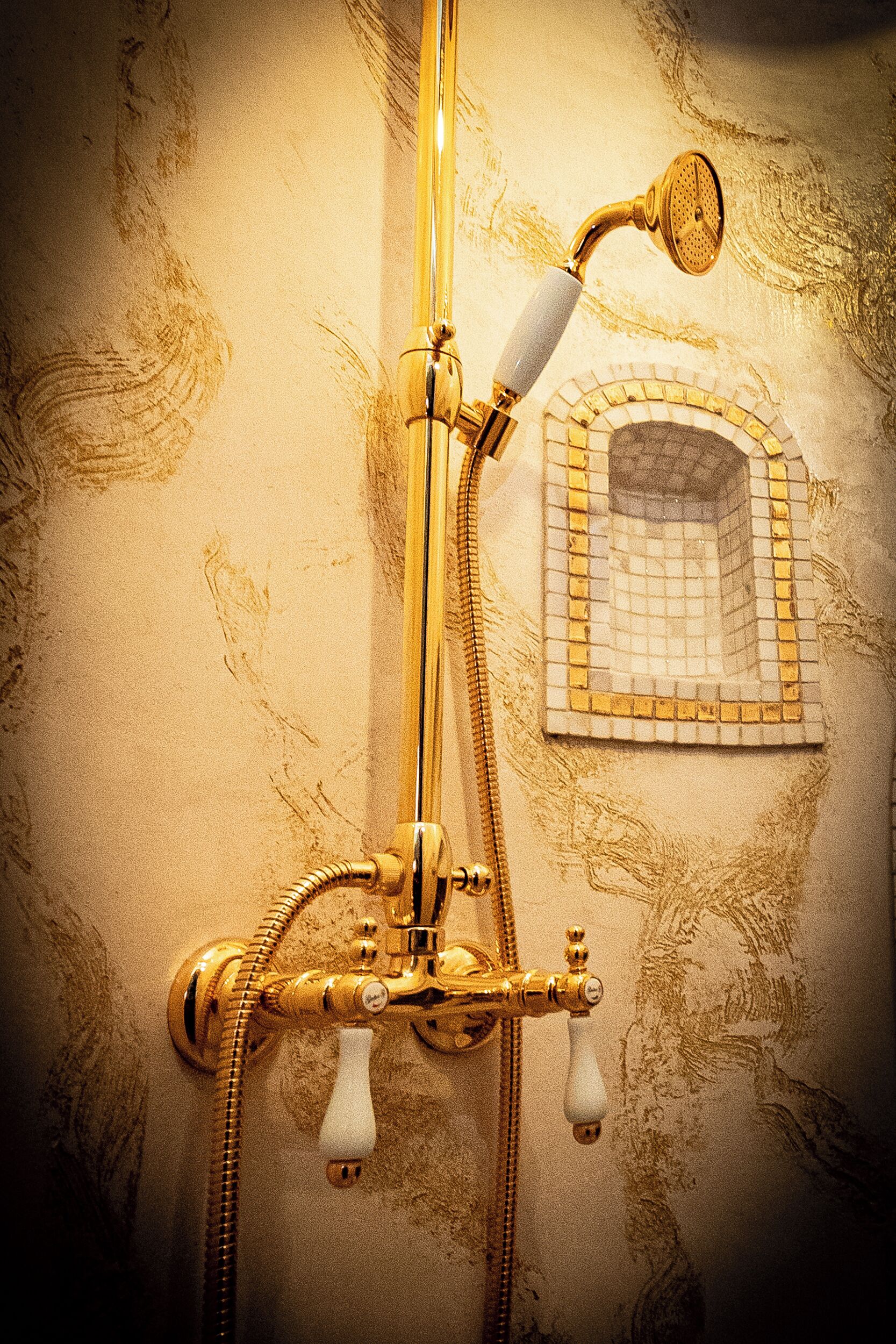 Un baño vintage con ducha de oro, lavamanos empotrado y diseño de mosaico.