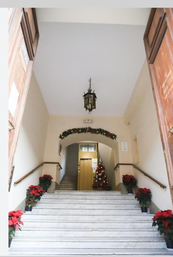 A staircase with a Christmas tree and poinsettias, leading to a door. - guest house eros suite (Rome)