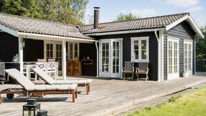 A wooden house with a covered patio, outdoor seating, and a chimney. - Pet friendly home in Sjællands Odde (Sjællands Odde)