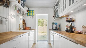 A narrow kitchen with white cabinetry, wooden countertops, and a view to the outside. - Pet friendly home in Sjællands Odde (Sjællands Odde)