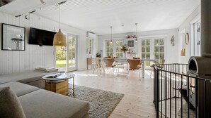 A spacious living area with a sofa, a dining table with chairs, and a kitchen area with a grill. - Pet friendly home in Sjællands Odde (Sjællands Odde)