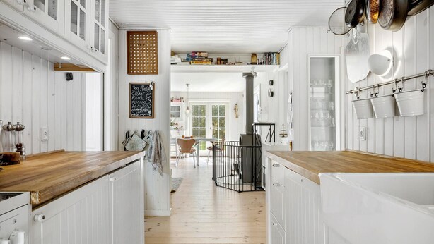 A narrow kitchen with wooden floors, white cabinets, and a central island. - Pet friendly home in Sjællands Odde (Sjællands Odde)