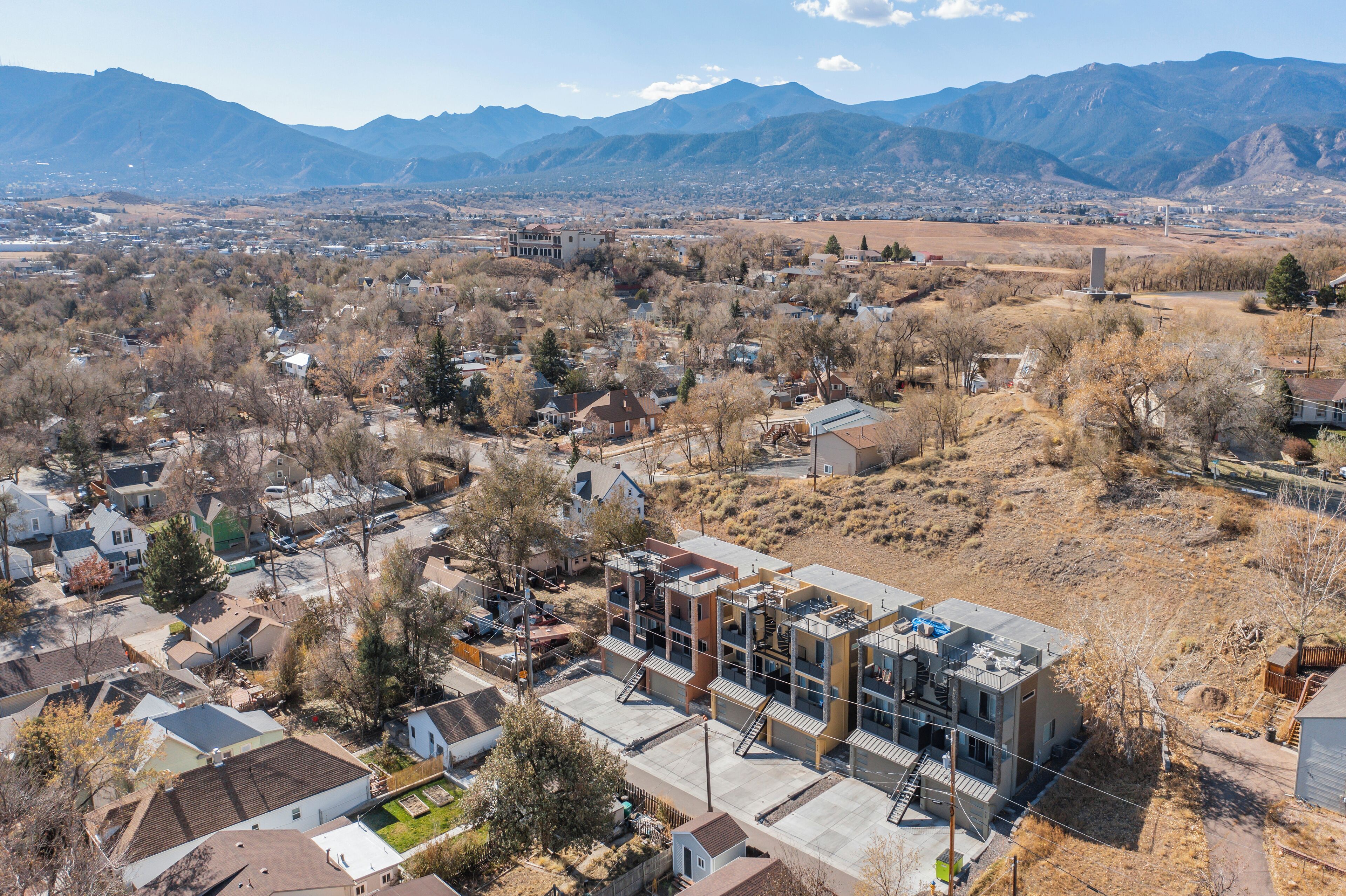 A residential area with houses, a modern building, and mountains in the background.