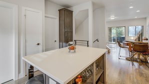 Cocina moderna con isla central, armarios empotrados y zona de comedor con una escalera que sube a otro nivel.