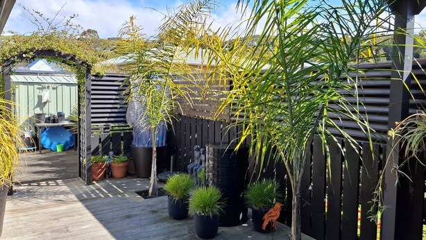 A wooden deck with potted plants, a metal fence, and a small shed. - Townhouse Haven - Modern, Spa, close to Nelson Central! Pets welcome. (Nelson)