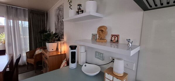 Ett modernt kök med vita skåp, en diskho, en bänkskiva och en krukväxt.