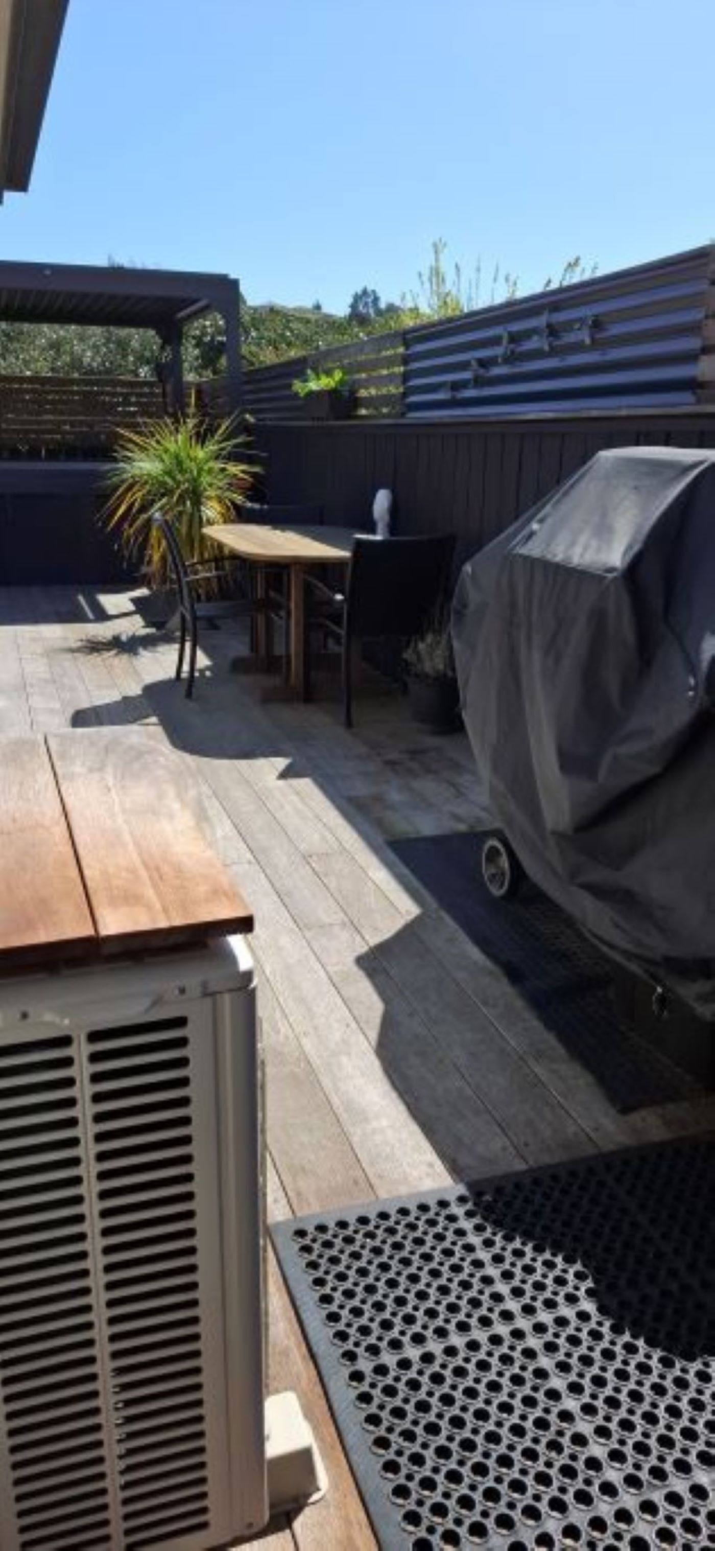 An outdoor patio area with a wooden table and chairs, a barbecue grill, and a covered grill.