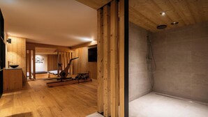 Un baño moderno y minimalista con detalles de madera, una zona de ducha y una máquina de ejercicios a la vista.