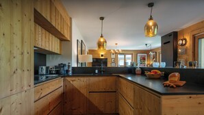 Una cocina moderna con armarios de madera, una isla grande, iluminación colgante y vistas al área de estar.