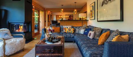 A cozy living room with a fireplace, a sofa set, a coffee table, and a framed animal picture on the wall.